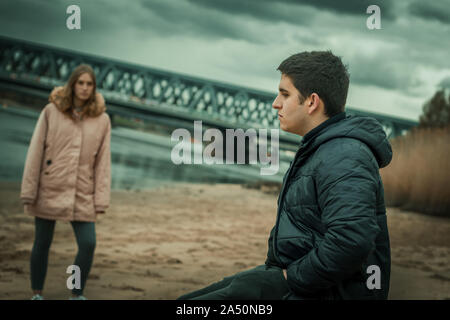 Nahaufnahme einer jungen nachdenklicher Mensch in der Natur sitzend mit seiner Freundin im Streit Stockfoto