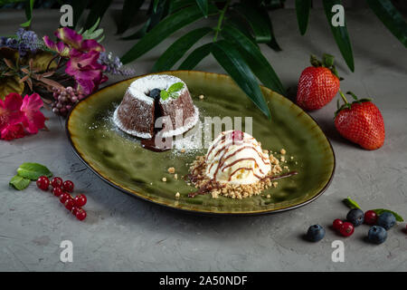 Schokoladen Flan und Kugel Eis in einem grünen Platte auf grauem Hintergrund Stockfoto