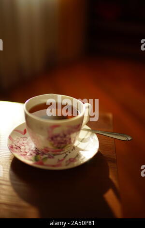 Schwarzer Tee in einem eleganten Schale auf der sonnigen Tabelle Stockfoto