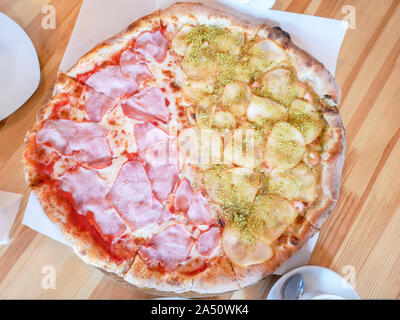 Schinken Pizza auf Holztisch. Pizza mit Speck, Schinken und Wurst auf Holztisch, Ansicht von oben Stockfoto