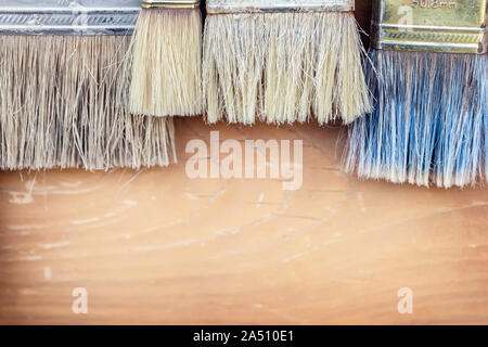 Close-up Set von alten Pant Bürsten auf rustikalen Holzmöbeln Hintergrund. Vintage schmutzige Pinsel Stockfoto