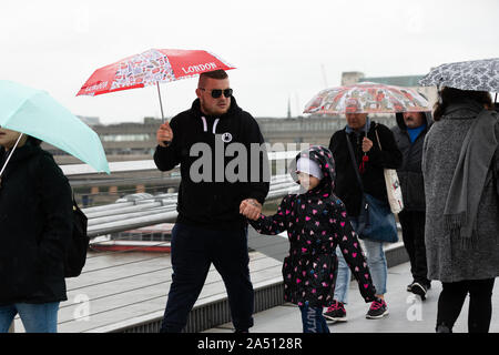 London. UK. 17. Oktober 2019. Touristen zu Fuß über die Millennium Bridge, gegenüber die St Paul's Kathedrale in London bei starkem Regen und nasse Wetter heute Nachmittag. Credit: Alamy leben Nachrichten Stockfoto