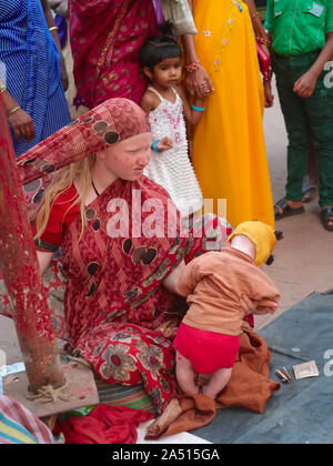 Die Mitglieder des Erweiterten Indischen albino Familie, eine Frau und ihr Kind, um Spenden in Udipi, Karnataka, Indien, durch eine Schar von Einheimischen umgeben Stockfoto