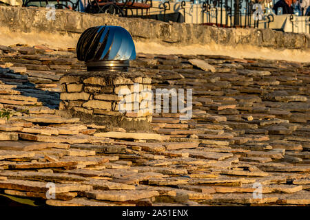 Rotierende metallic mit Blautönen spinner Schornstein Schlot auf Stein Ziegeldach, Saranda, Albanien, Foto in der Goldenen Stunde der Frühling Abend genommen Stockfoto