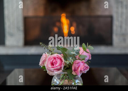 Innenraum Foto eines Rosen Blumenstrauß mit Kamin im Hintergrund. Selektive konzentrieren. Von der Seite. Stockfoto