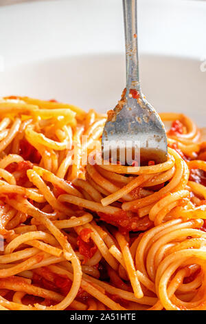 Gabel close-up in Italienische Spaghetti Pasta in weiße Platte mit Ketchup Soße umhüllt, Bild vertikal. Stockfoto