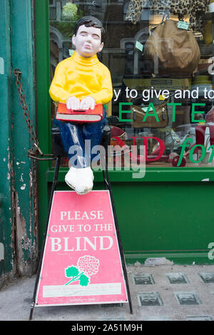 Bitte den Blinden Sammelbox und Abbildung außerhalb einer Charity Shop in Twickenham, London, UK Geben Stockfoto