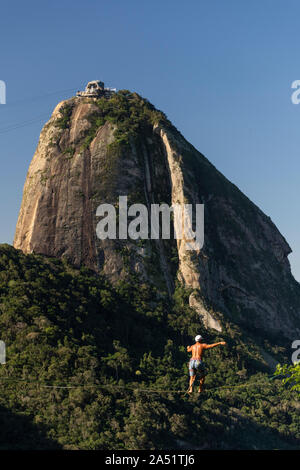 Slackliner zu Fuß auf Highline mit schöner Landschaft und Zuckerhut auf der Rückseite, Rio de Janeiro, Brasilien Stockfoto