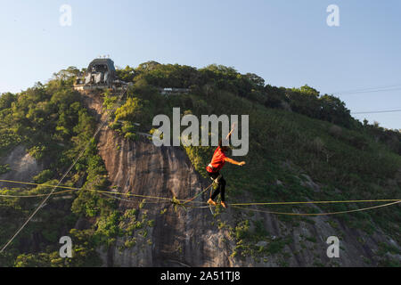 Slackliner zu Fuß auf Highline mit schöner Landschaft und Zuckerhut auf der Rückseite, Rio de Janeiro, Brasilien Stockfoto