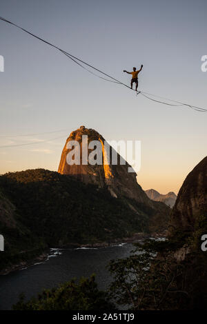 Slackliner zu Fuß auf Highline mit schöner Landschaft und Zuckerhut auf der Rückseite, Rio de Janeiro, Brasilien Stockfoto