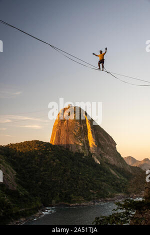 Slackliner zu Fuß auf Highline mit schöner Landschaft und Zuckerhut auf der Rückseite, Rio de Janeiro, Brasilien Stockfoto