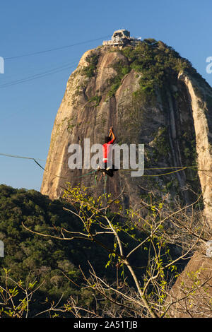 Slackliner zu Fuß auf Highline mit schöner Landschaft und Zuckerhut auf der Rückseite, Rio de Janeiro, Brasilien Stockfoto