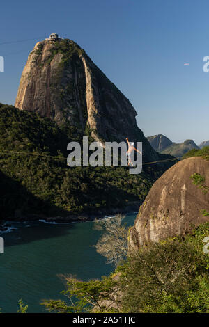 Slackliner zu Fuß auf Highline mit schöner Landschaft und Zuckerhut auf der Rückseite, Rio de Janeiro, Brasilien Stockfoto