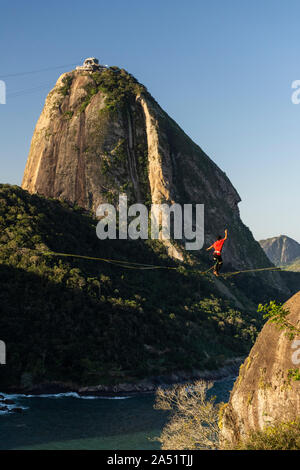 Slackliner zu Fuß auf Highline mit schöner Landschaft und Zuckerhut auf der Rückseite, Rio de Janeiro, Brasilien Stockfoto