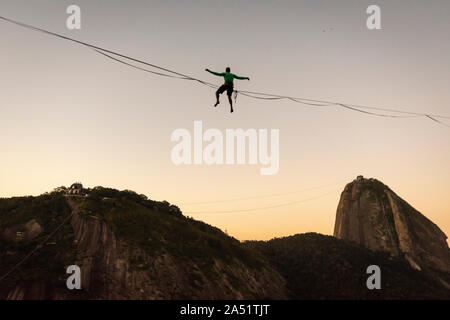 Slackliner zu Fuß auf Highline mit schöner Landschaft und Zuckerhut auf der Rückseite, Rio de Janeiro, Brasilien Stockfoto