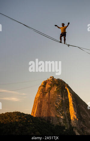 Slackliner zu Fuß auf Highline mit schöner Landschaft und Zuckerhut auf der Rückseite, Rio de Janeiro, Brasilien Stockfoto