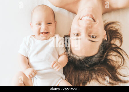 Mutter und Neugeborenem Sohn reckte lachend im Bett Stockfoto