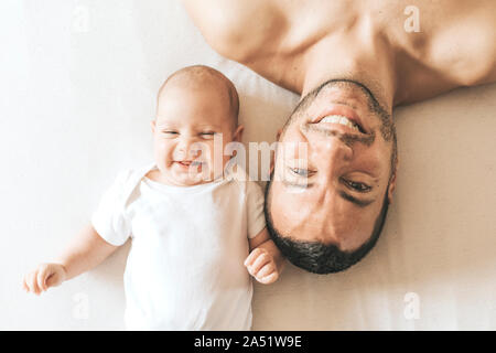 Vater und neugeborenen Sohn reckte lachend im Bett Stockfoto