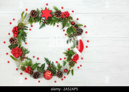 Weihnachten Kranz mit Christbaumkugel Dekorationen, lose Stechpalme Beeren und Winter Flora auf rustikalem Holz Hintergrund mit kopieren. Stockfoto