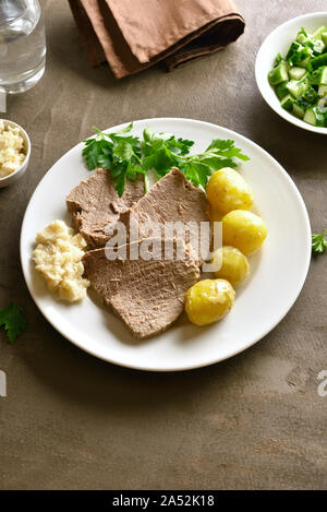 Gekochtes Rindfleisch mit Kartoffeln und Meerrettich (Tafelspitz) auf braunem Hintergrund. Stockfoto