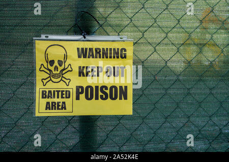 Gedruckte Schädel Totenkopf Schild mit Bindemittel zip in einen Zaun in eine Baustelle gebunden an der Warning out Gift halten Stockfoto