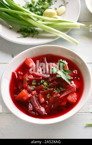 Traditionelle Ukrainisch Russisch-Suppe (Borschtsch) mit den Gruenen. Rote-bete-Suppe in der Schüssel auf weißem Holz- Hintergrund. Ansicht von oben, flach Stockfoto