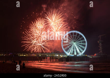 Sich drehende Riesenrad mit Feuerwerk an der Pier in der Nähe von Scheveningen, Den Haag, Niederlande. Stockfoto