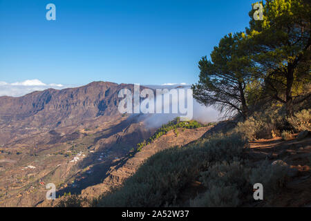 Gran Canaria, Oktober, Wolken fließen in Caldera de Tejeda von rechts über bergpass Cruz De Tejeda, Los Moriscos Klippen von wildfir Stockfoto