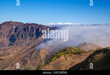 Gran Canaria, Oktober, Wolken fließen in Caldera de Tejeda von rechts über bergpass Cruz De Tejeda, Los Moriscos Klippen von wildfir Stockfoto