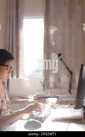 Eine Frau, die Verfasser der Eingabe über die Tastatur auf dem Schreibtisch Stockfoto