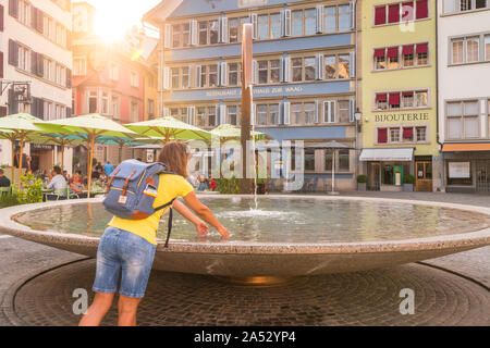 Frau erfrischend ihre Hände in Munsterhof Brunnen, Zürich berühmten Platz, Schweiz Stockfoto