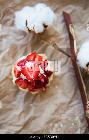 Schöne Muffin mit frischen Erdbeeren liegt auf Handwerk Papier, close-up. Stockfoto