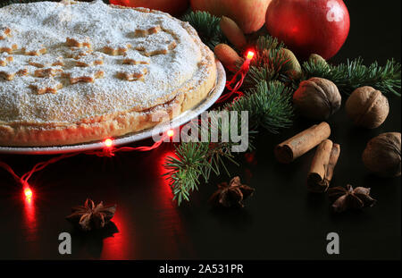 Hausgemachte amerikanische traditionellen Urlaub pie. Apfelkuchen mit Stars, Zimt, Apfel, Sternanis, Lichter und Fir-Niederlassung in dunklen Hintergrund eingerichtet Stockfoto