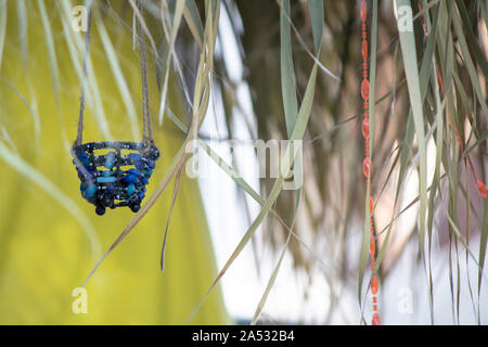 Dekorativer Korb hängen auf dem Dach. Getrocknete Blätter nach unten hängen vom Dach. Raupe Dekorationen auf Korb. Stockfoto