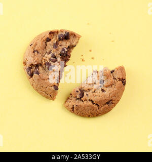 Chocolate Chip Cookie in zwei gebrochene auf gelben Hintergrund. Ansicht von oben Stockfoto