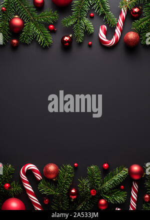 Schwarze Weihnachten und Neujahr Hintergrund. Dekorative Grenze von tannenzweigen, Weihnachtskugeln und Zuckerstangen Stockfoto