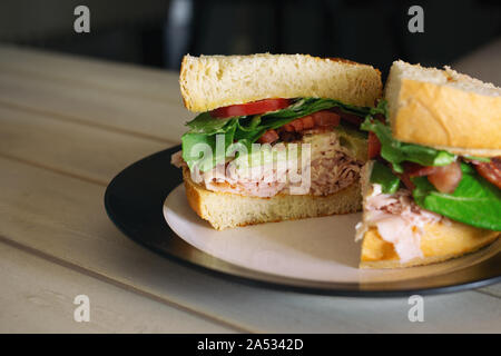 Die Türkei Club Sandwich in der Hälfte mit Speck, Tomate, Avocado und Salat auf frisch gebackenem Sauerteigbrot. Stockfoto