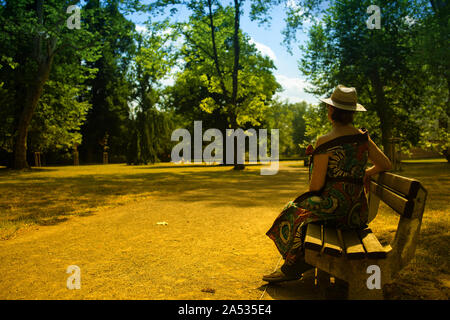 Elegante Frau in einen Hut in einem Park auf einer Bank sitzen, Tschechische Republik Stockfoto