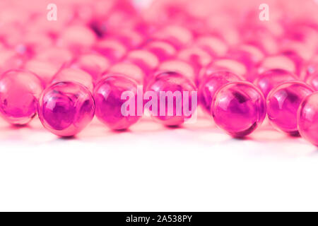 Kunststoff rosa sphärischen Kugel Kapseln mit selektiven Fokus auf weißem Hintergrund. Stockfoto