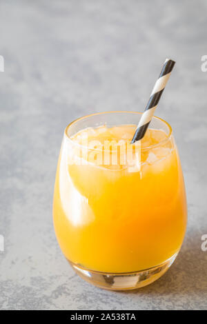 Ein Orangensaft trinken mit gestoßenem Eis und ein umweltfreundliches Papier, Stroh. Das Stroh wird gestreift schwarz und weiß. Vertikale Foto mit Raum für Stockfoto