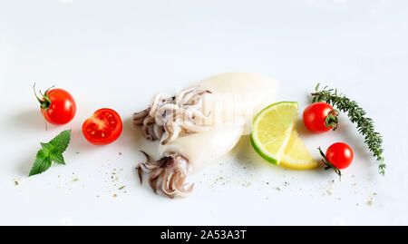 Frischer Tintenfisch mit Zitrone, Limone, Kräuter und Tomaten auf weißem Hintergrund Stockfoto