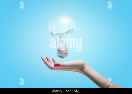 Woman's Hand mit Öffnen Sie Palm, als ob ungefähr Halten von einer elektrischen Lampe, die in der Luft schweben mit Wasser im Inneren der Lampe zu nehmen. Stockfoto