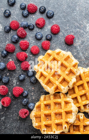Waffeln mit Heidelbeeren und Himbeeren auf alten Küchentisch. Ansicht von oben. Stockfoto