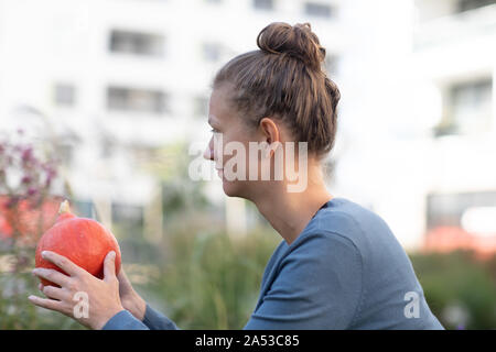 Junge Frau in einem Garten mit einem Kürbis Stockfoto