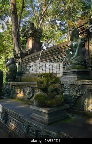 Ein paar Affen pflegen sich gegenseitig beim Sitzen auf einem Tempel Wand im Dschungel, in Ubud, Bali Stockfoto