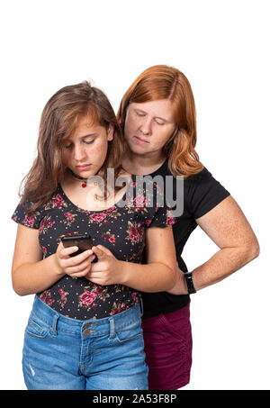 Vertikale studio Schoß einer Mutter, die gerade über die Schulter ihrer Tochter, als sie ihr Mobiltelefon verwendet. Weißer Hintergrund. Stockfoto