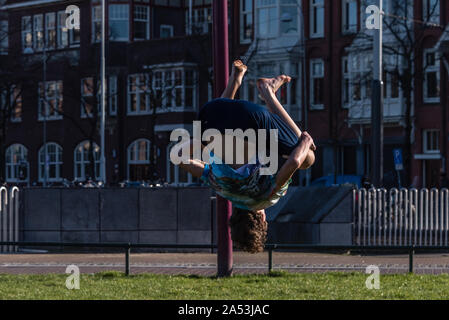 Amsterdam, Holland, 25. Februar 2019 Straße spiegeln Junge auf dem Gras der Museumplein in Amsterdam in seine Shorts an einem sonnigen Tag Stockfoto