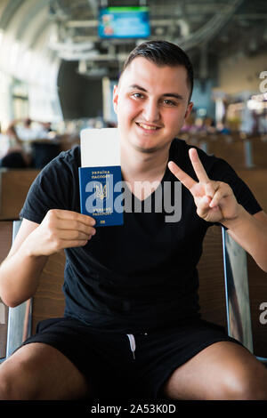 Young Travel Mann warten auf Ebene im Flughafen, während die im Besitz eines ukrainischen Pass in den Händen. Stockfoto