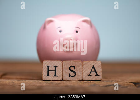 HSA Health Savings Account Holzklötze in der Nähe von sparschwein am Tisch Stockfoto