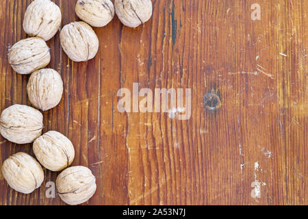 Walnüsse in der Schale an der Seite eines alten Holz Hintergrund Stockfoto